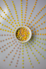 Geometric pattern of colour cereal loops, with a full bowl