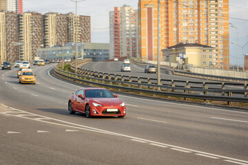 The car is driving on a high-speed wide highway. Behind you can see the multi-storey buildings of a large city