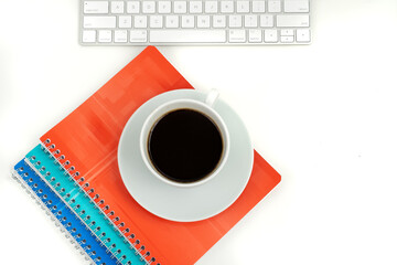 Obraz na płótnie Canvas stylish flat lay: a cup of black coffee, colorful notebooks and a modern keyboard on a white office table
