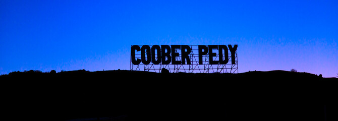 Banner panorama of the welcome road sign of Coober Pedy mining underground town in Australia at night. Located in the South Australian outback desert.