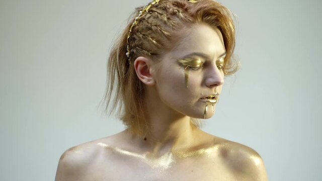 Fashion art skin. Gold face art. Sensual girl with golden makeup. Woman gold portrait closeup.