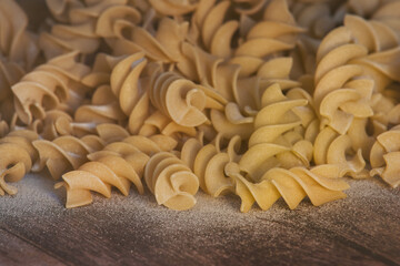 A pile of Italian pasta spindles lying on a wooden table.