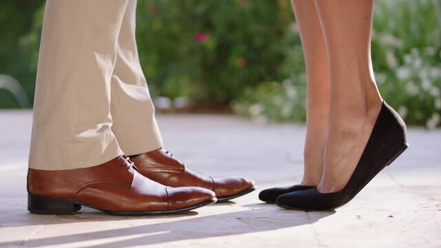 Close up on feet of young couple standing outside, standing up on tippy toes
