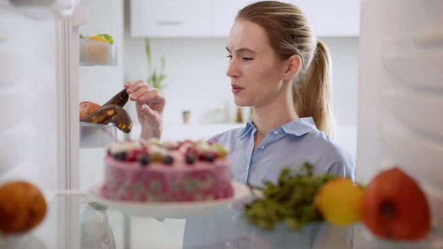 Woman squints because of stench something disgusting, unpleasant smell from her fridge. View from inside broken fridge