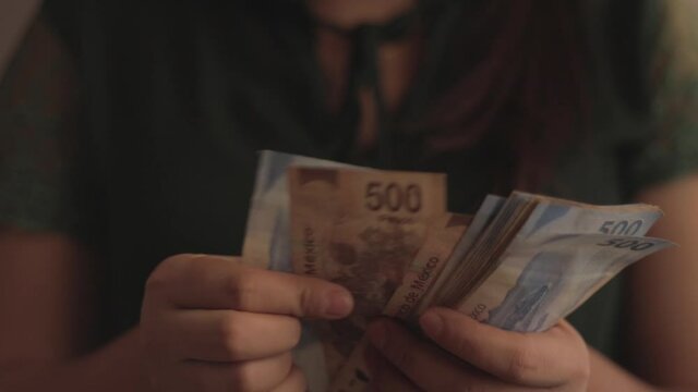Woman showing five hundred Mexican pesos bills.