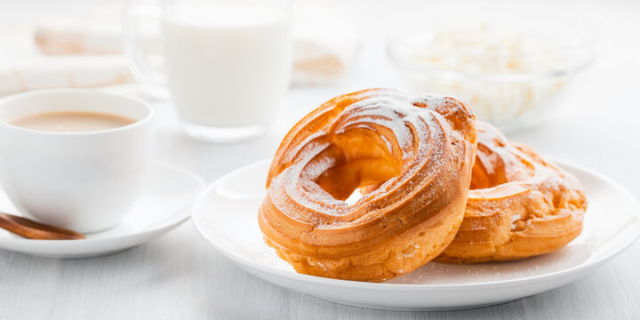 Morning coffee with cake. Custard rings, coffee, cream, cottage cheese on a white wooden table