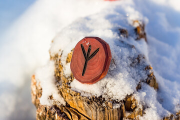 Rune inverted Algiz (Elhaz) carved from wood in the snow