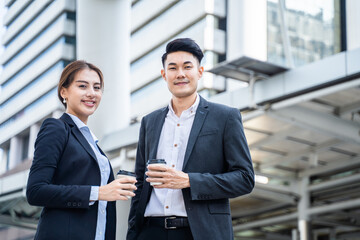 Asian young business people standing in the city, holding coffee cup.