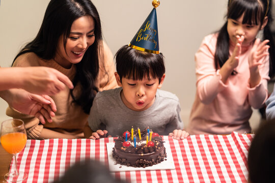 Asian Young Boy Blowing Candles On His Birthday Cake, Birthday Party.