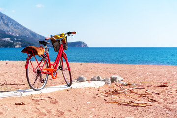 Red walking bike with basket full of necessary things for relaxing on beach, stands on boardwalk on...