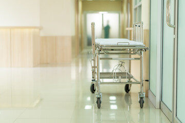 Empty nursing bed on hospital hallway in front of  operating room with copyspace. Healthcare concept during Covid-19 pandemic