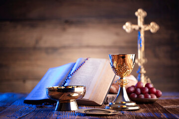 Catholic religion concept. Catholic symbols composition. The Cross, Holy Bible and golden chalice on the altar.