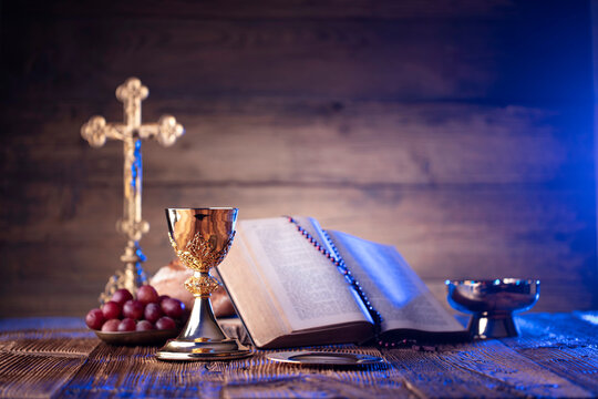 Catholic religion concept. Catholic symbols composition. The Cross, Holy Bible and golden chalice on the altar.