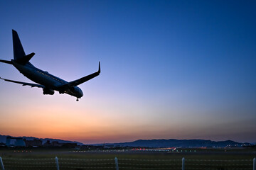 美し夕焼けを背景に着陸する飛行機のシルエット
