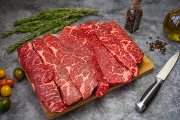 Sliced ​​raw piece of marble beef brisket on a cutting board.