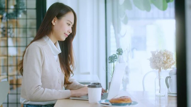 young attractive asian female wear casual cloth hand use smartphone and laptop device comminication social contact in cafe restaruant sit at counter next to big window daylight