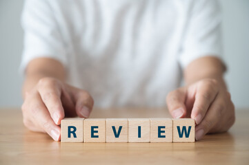 Review concept. The word REVIEW on wooden cube block on wood table