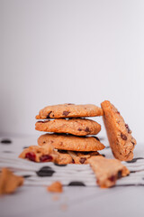 Piles of delicious chocolate chip cookies on a white plate with a milk bottle. Pastry utensils with white linen napkins on a wooden table. Delicious on a white plate with a bottle of milk.