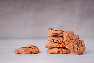 Piles of delicious chocolate chip cookies on a white plate with a milk bottle. Pastry utensils with white linen napkins on a wooden table. Delicious on a white plate with a bottle of milk.