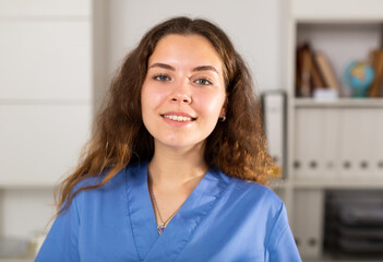 Portrait of european doctor female in blue shirt standing in white medical office in clinic