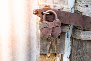 Iron rusty lock with a key. Closed door.