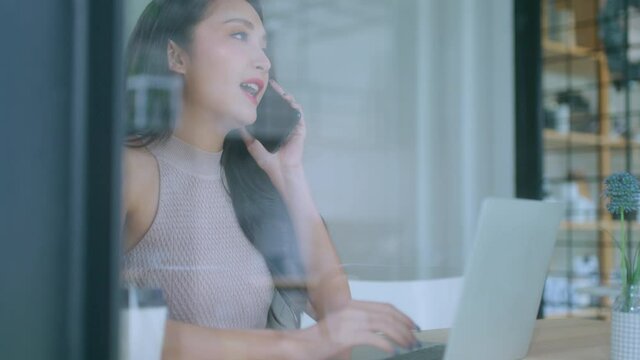 young attractive asian female wear casual cloth hand use smartphone and laptop device comminication social contact in cafe restaruant sit at counter next to big window daylight