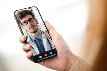 Patient making video call with doctor online via mobile phone, home medical consulation service and telemedical concepts