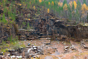 Abandoned granite quarry in the autumn forest.