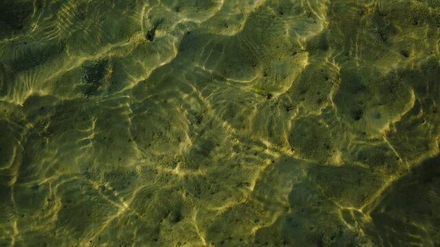 The sea wave ripples pattern texture, reflecting the sunlight and being clear to see the serene sandy bottom. Peaceful beaches on island are beautiful landscapes and perfect for long vacation.