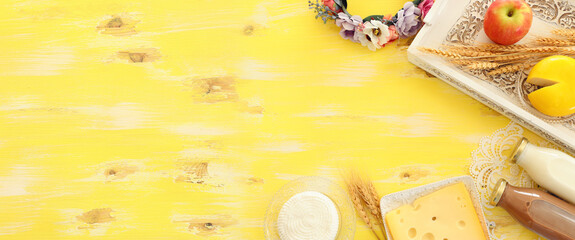 Top view photo of dairy products over yellow wooden background. Symbols of jewish holiday - Shavuot