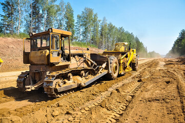 a yellow tractor scraper levels the ground. Construction of a new road.