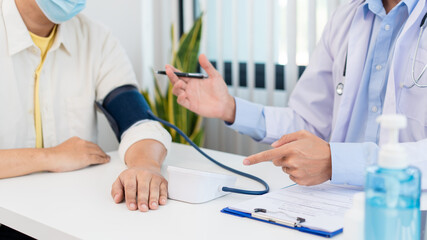 Medical concept a male doctor measuring blood pressure of patient by using sphygmomanometer before examination