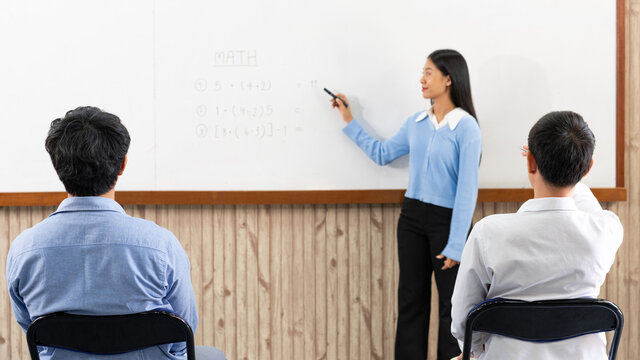 Educational concept a young smart female teacher explaining decision of hard math in a classroom before Covid-19 epidemic