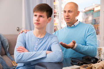 Portrait of father supporting his upset teenage son at home