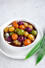 Kolak biji salak pelangi or sweet potato porridge in white bowl, made from sweet potato, sago flour, brown sugar and coconut milk. It made for takjil or dessert.