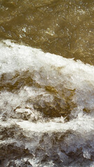 The first ice on the bank of a muddy reservoir in winter. Background for design.