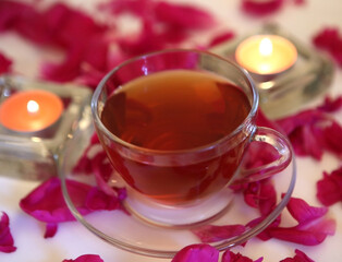 cup with tea, petals and burning candles