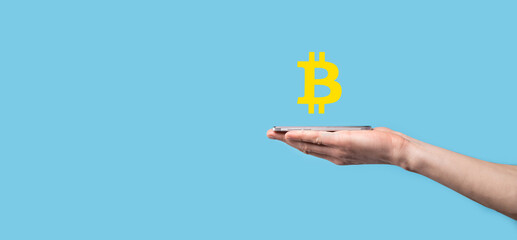 Male hand holding a bitcoin icon on blue background. Bitcoin Cryptocurrency Digital Bit Coin BTC Currency Technology Business Internet Concept.