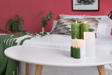 Burning candles on table in bedroom