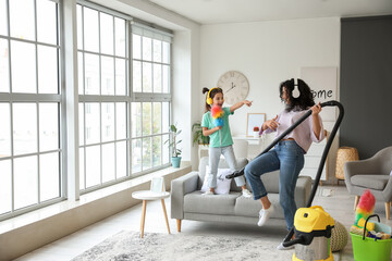 Mother and daughter having fun while hoovering floor in flat