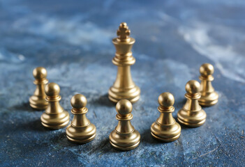 Golden king and pawns on color background