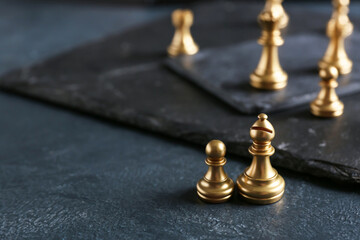 Golden pawn and bishop on dark background