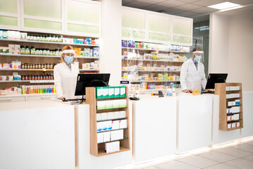Intérieur de la pharmacie avec des médicaments et des caissiers de pharmaciens travaillant pendant la pandémie du virus corona.
