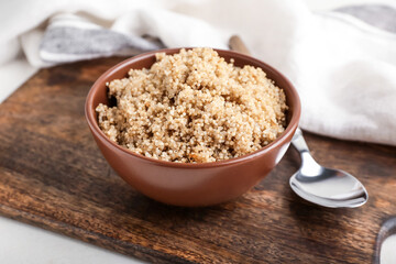 Bowl with tasty quinoa and spoon on table