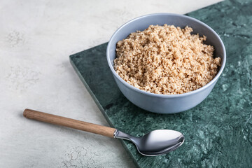 Bowl with tasty quinoa and spoon on light background