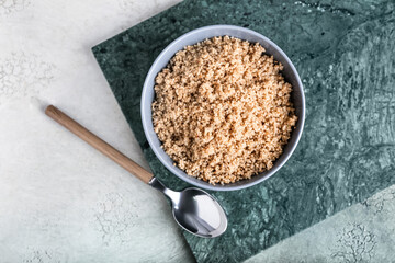 Bowl with tasty quinoa and spoon on light background