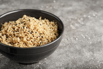 Bowl with tasty quinoa on grey background, closeup