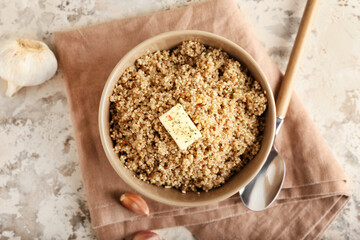 Bowl with tasty quinoa, butter and garlic on grunge background