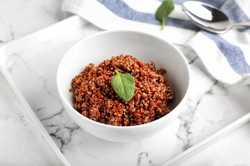 Bowl with tasty quinoa on light background