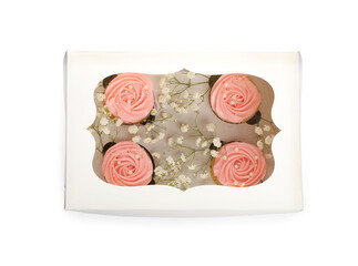 Box with tasty cupcakes and flowers on white background